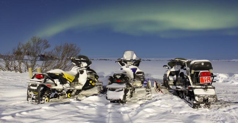 Sneeuwscooter rijden tijdens noorderlicht in IJsland